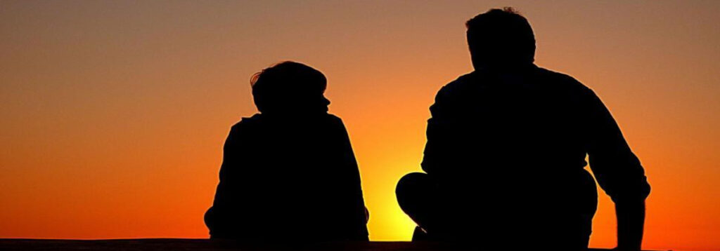 Two people seated together in a calm, understated setting, suggesting quiet connection.